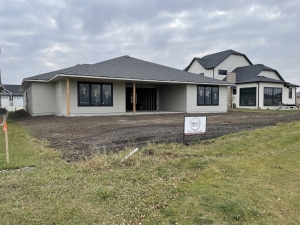 Recently completed Rosewood Homes custom home exterior with dark grey siding stone accents and professional landscaping Sioux Falls South Dakota