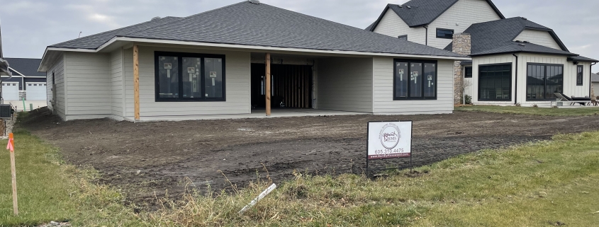 Recently completed Rosewood Homes custom home exterior with dark grey siding stone accents and professional landscaping Sioux Falls South Dakota